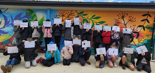 School children holding books they have made during Claire Saxby school visit